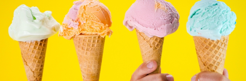 Four ice cream cones in a line. White, orange, pink and blue ice cream cones