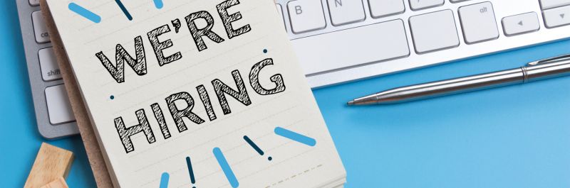 Teen Summer Intern A white keyboard with a notepad resting on top with the note we're hiring