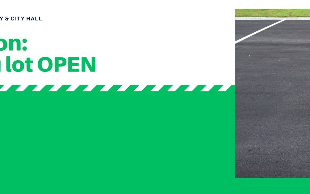Sign indicating "Parking lot OPEN" for Prescott Public Library & City Hall, with a green and white design and an asphalt parking lot on the right.